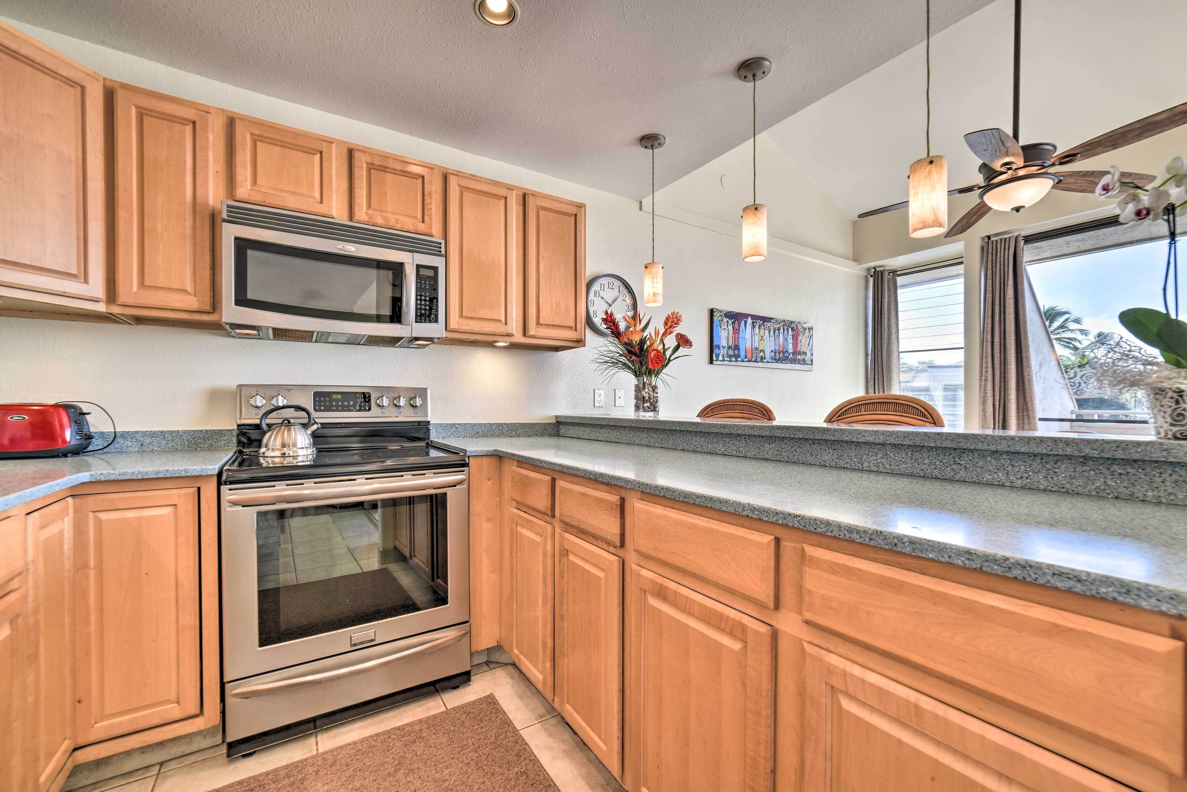 A kitchen with wooden cabinets, stainless steel appliances, a clock, and pendant lights.
