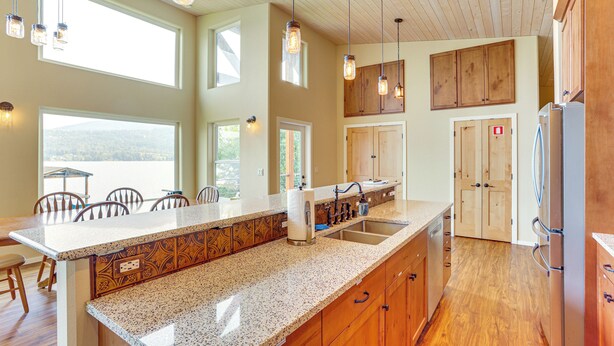 A kitchen with a large island, wooden cabinets, and a view of the outdoors. - Lake Whatcom House w/ Private Hot Tub + Dock (Bellingham)