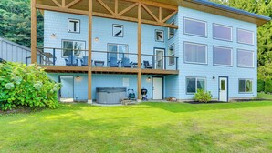 A two-story building with a balcony, a hot tub, and a well-maintained lawn. - Lake Whatcom House w/ Private Hot Tub + Dock (Bellingham)
