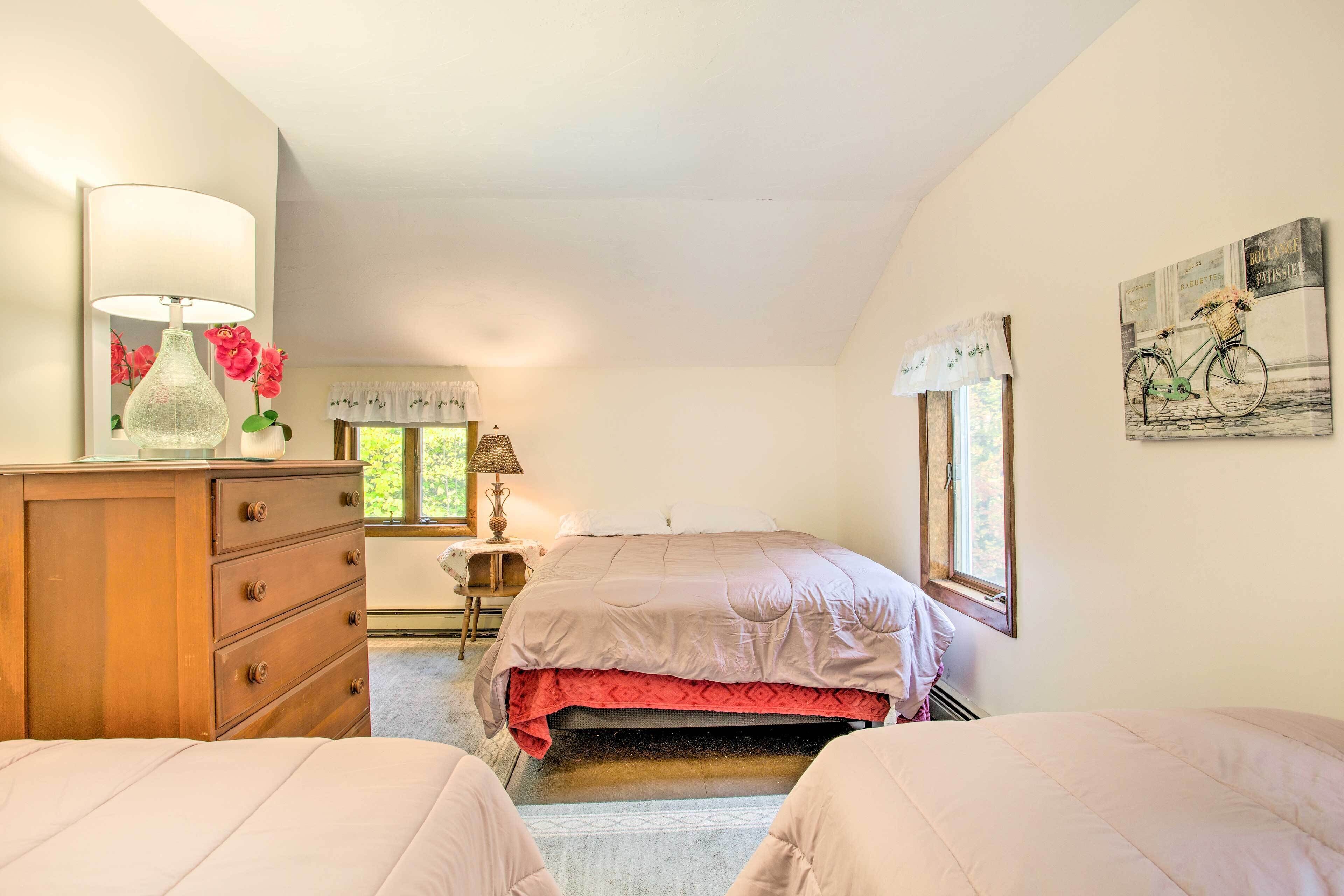 A bedroom with a bed, a dresser, a lamp, and a window.