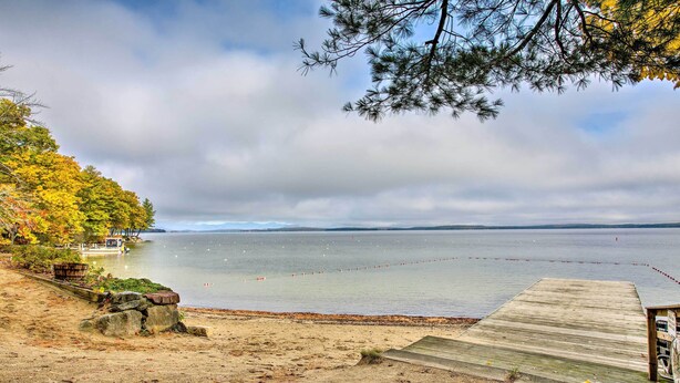 A beach with a wooden dock, a small boat, and a distant shoreline.