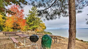 A lakeside picnic area with picnic tables, a grill, and a covered barbecue.