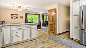 A spacious kitchen with white cabinetry, a large island, and a built-in stainless steel refrigerator.