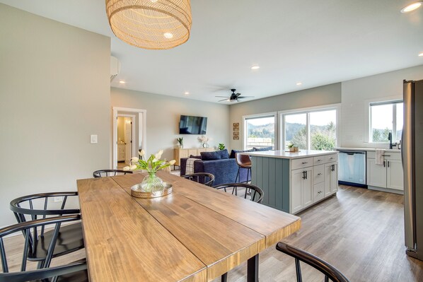 A modern kitchen with a wooden dining table, chairs, and a ceiling fan. - Charming Florence Home w/ Fire Pit & River Views! (Florence)