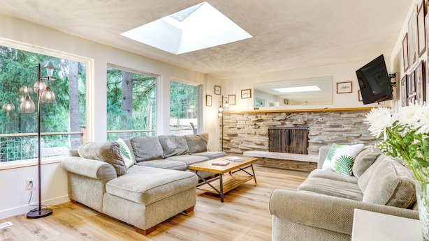 A modern living room with a sectional sofa, a coffee table, and a stone fireplace. - Classic Woodinville Wine Country Escape! (Woodinville)