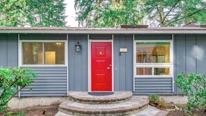 A house with a red door, a front porch with steps, and a small garden area. - Classic Woodinville Wine Country Escape! (Woodinville)