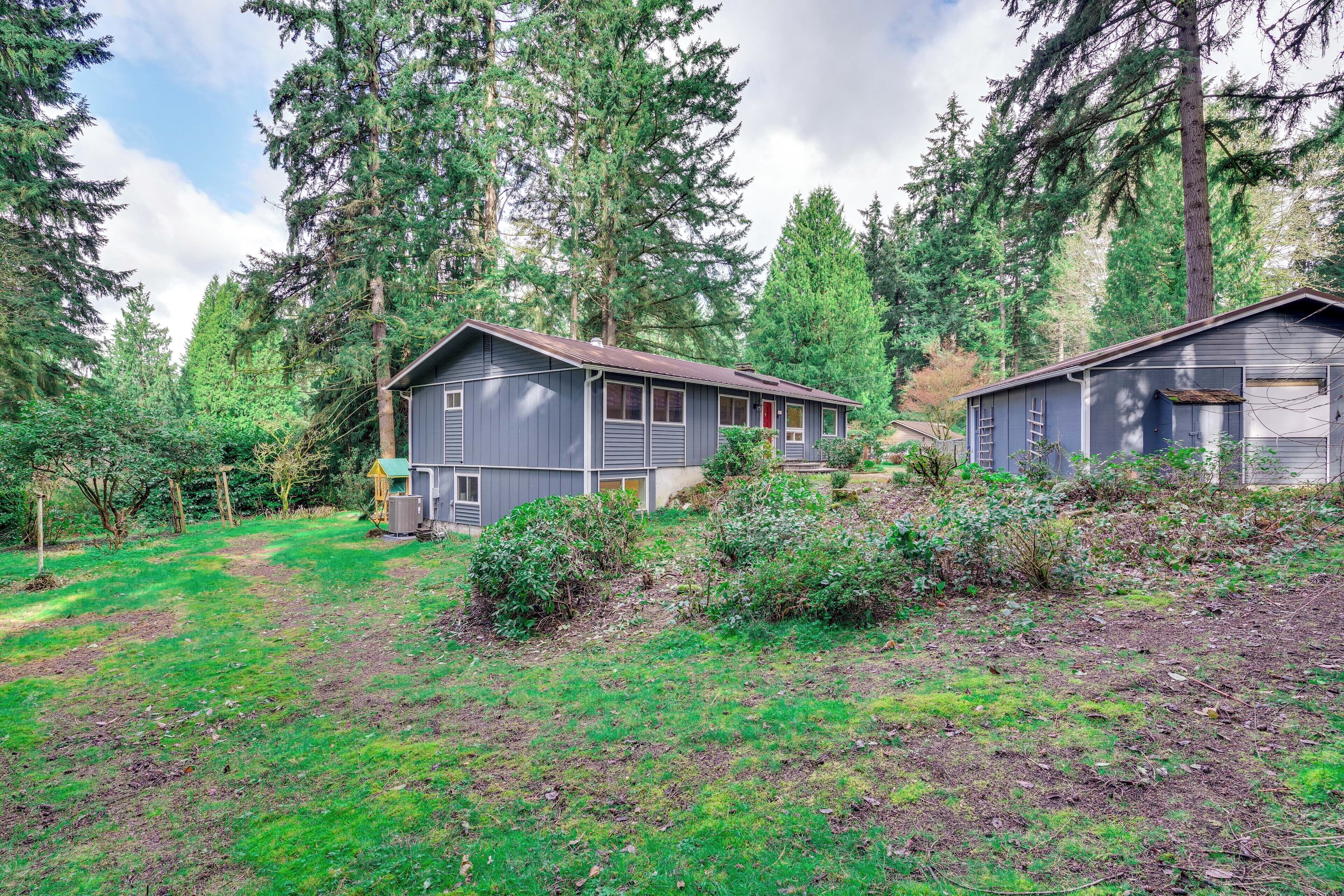 A cabin with a small porch and a garage, surrounded by dense forest.