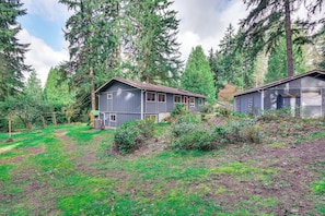 A cabin with a small porch and a garage, surrounded by dense forest.