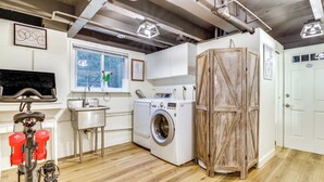 A laundry area with a washing machine, a sink, and a wooden wardrobe. - Classic Woodinville Wine Country Escape! (Woodinville)
