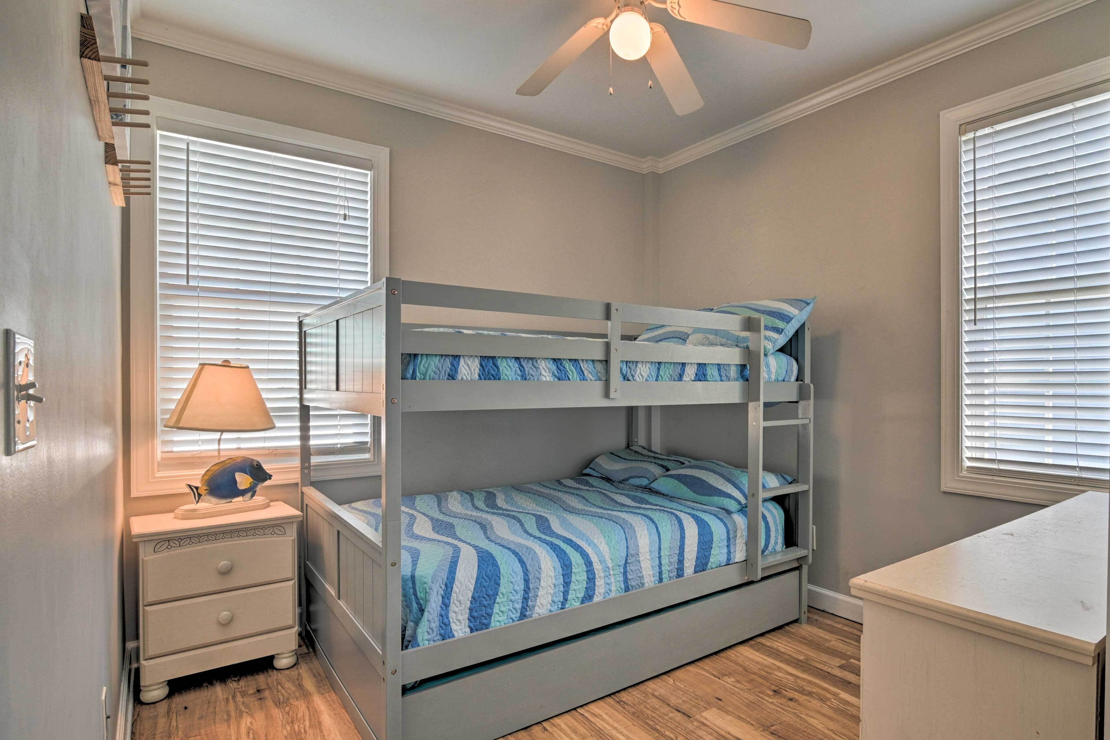 Een slaapkamer met stapelbed, plafondventilator, bedlamp en een klein nachtkastje.