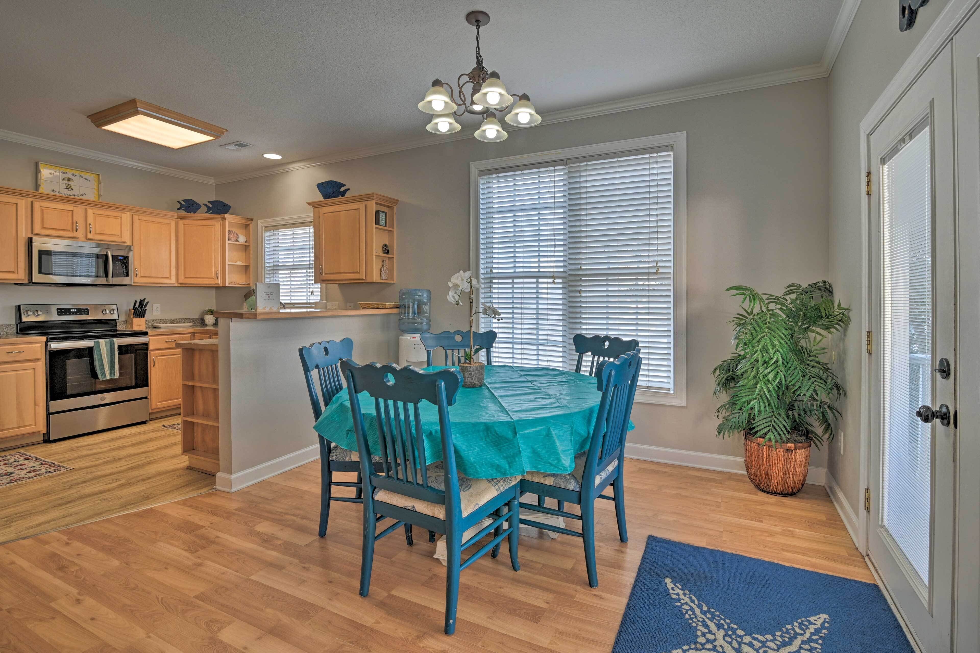 A kitchen with wooden cabinets, a microwave, and a dining area with a table and chairs.