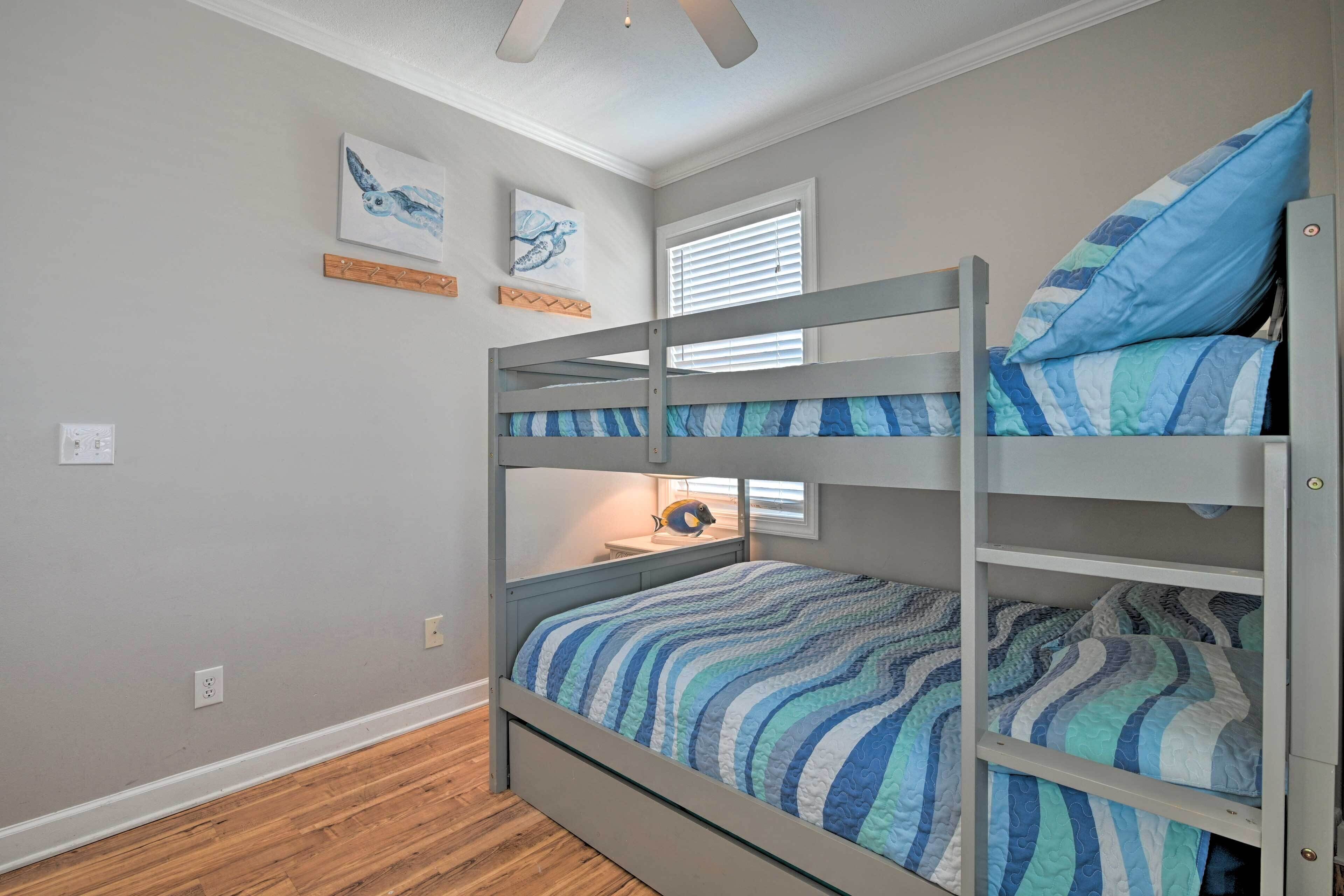 A bunk bed with striped bedding, a ceiling fan, and artwork on the walls.