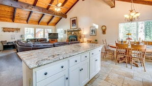 A spacious living room with a large island, a fireplace, and a dining area with wooden chairs and a table. - Spacious House w/ Deck & Grill in South Lake Tahoe (South Lake Tahoe)