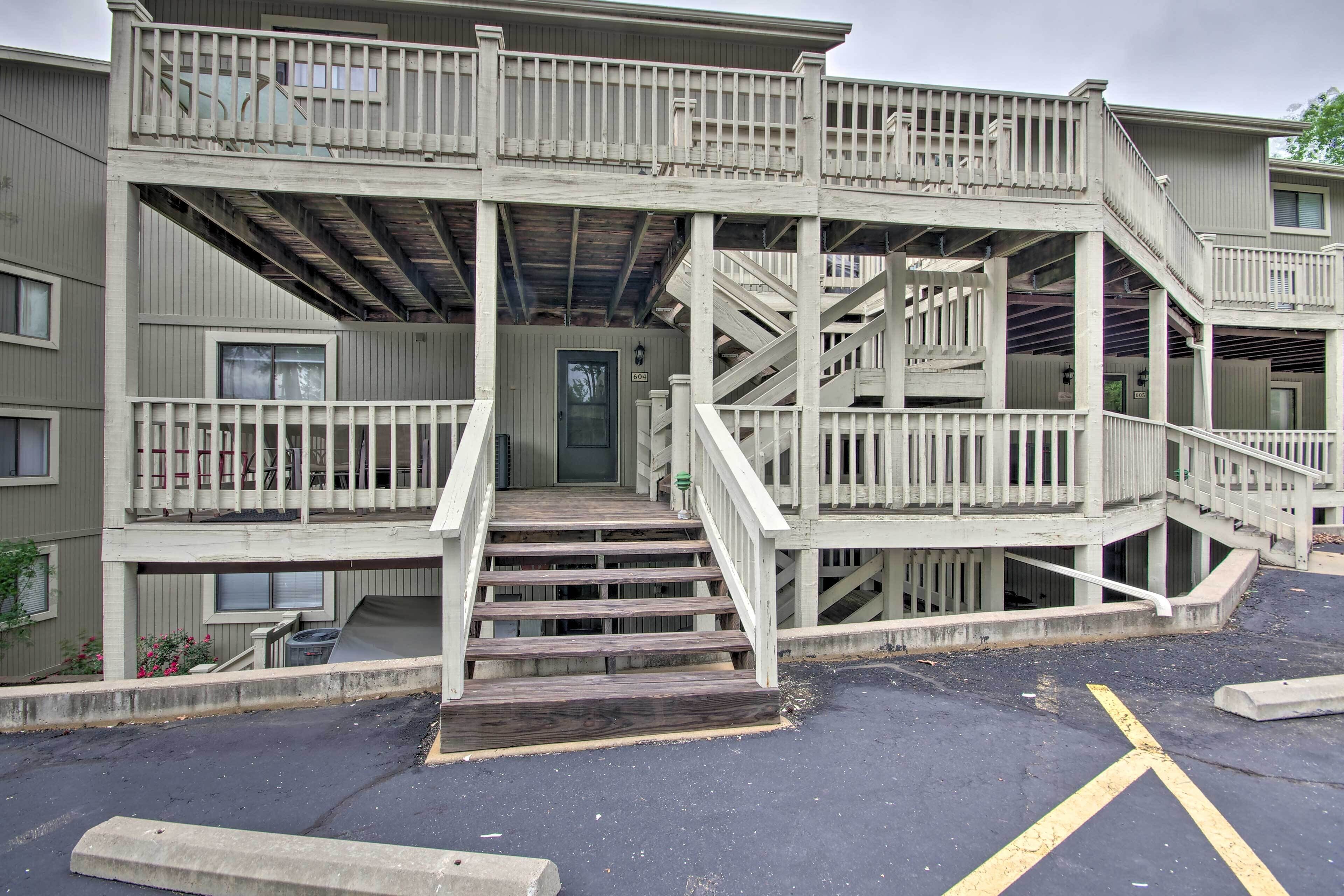 A multi-story building with a central staircase, balconies, and a parking area.