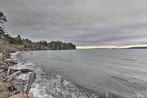 Vista costera con costa rocosa, árboles y un mar tranquilo bajo un cielo nublado.