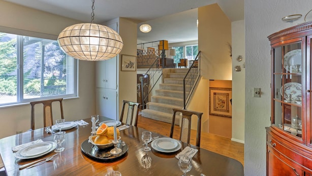 A dining area with a wooden table set for four, a chandelier, and a staircase leading to an upper level. - Lake Almanor Country Club Home w/ Views! (Westwood)