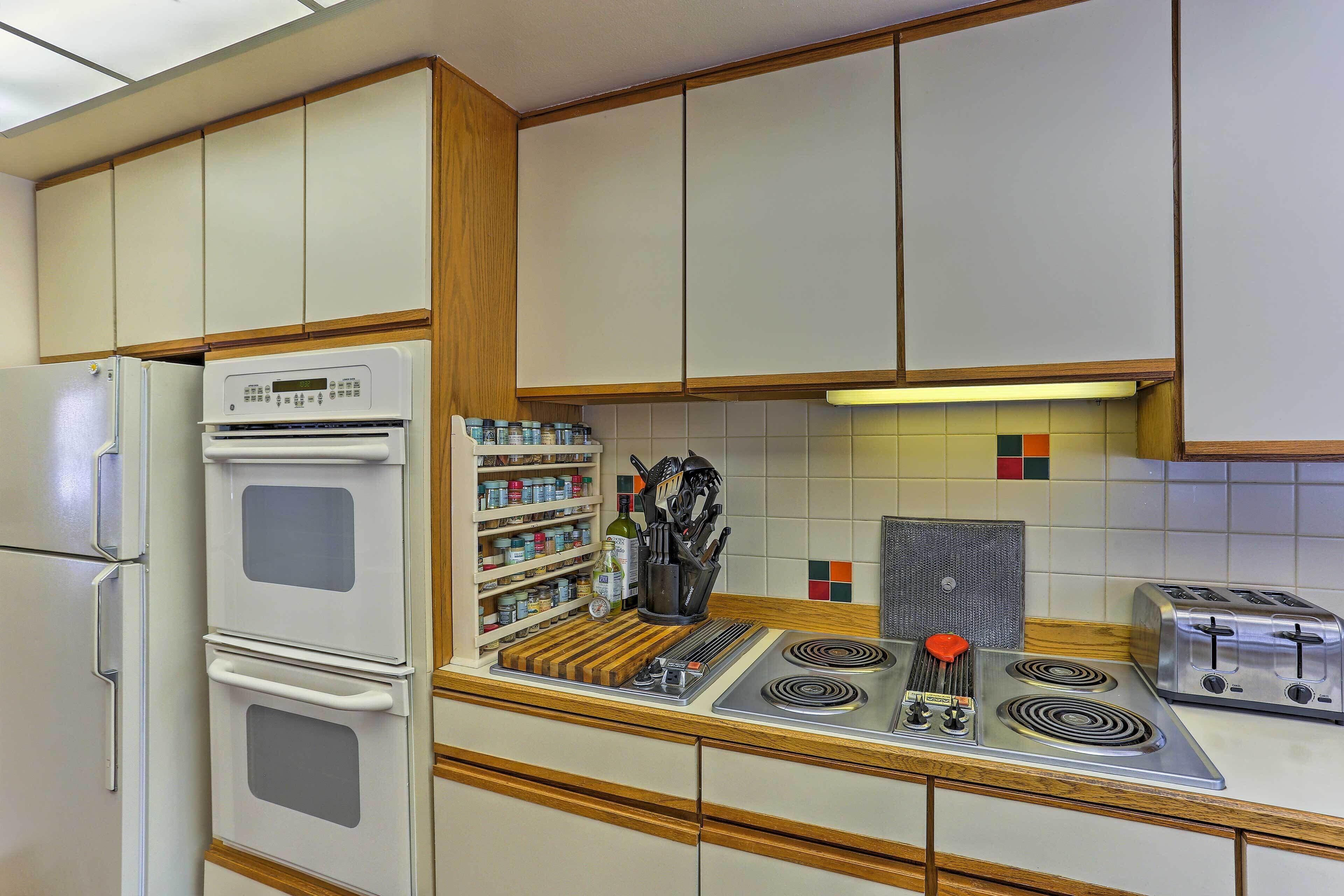 Een keuken met een dubbele oven, een fornuis, een broodrooster en een kruidenrek.