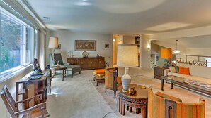 A spacious living room with a large window, a sofa, a dining table, and a fireplace. - Lake Almanor Country Club Home w/ Views! (Westwood)