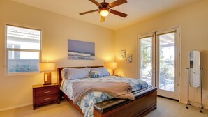 A bedroom with a bed, nightstands, a ceiling fan, a window, and a door leading to a balcony. - 1 Mi to Coachella: Serene Retreat w/ Pool Access (Indio)