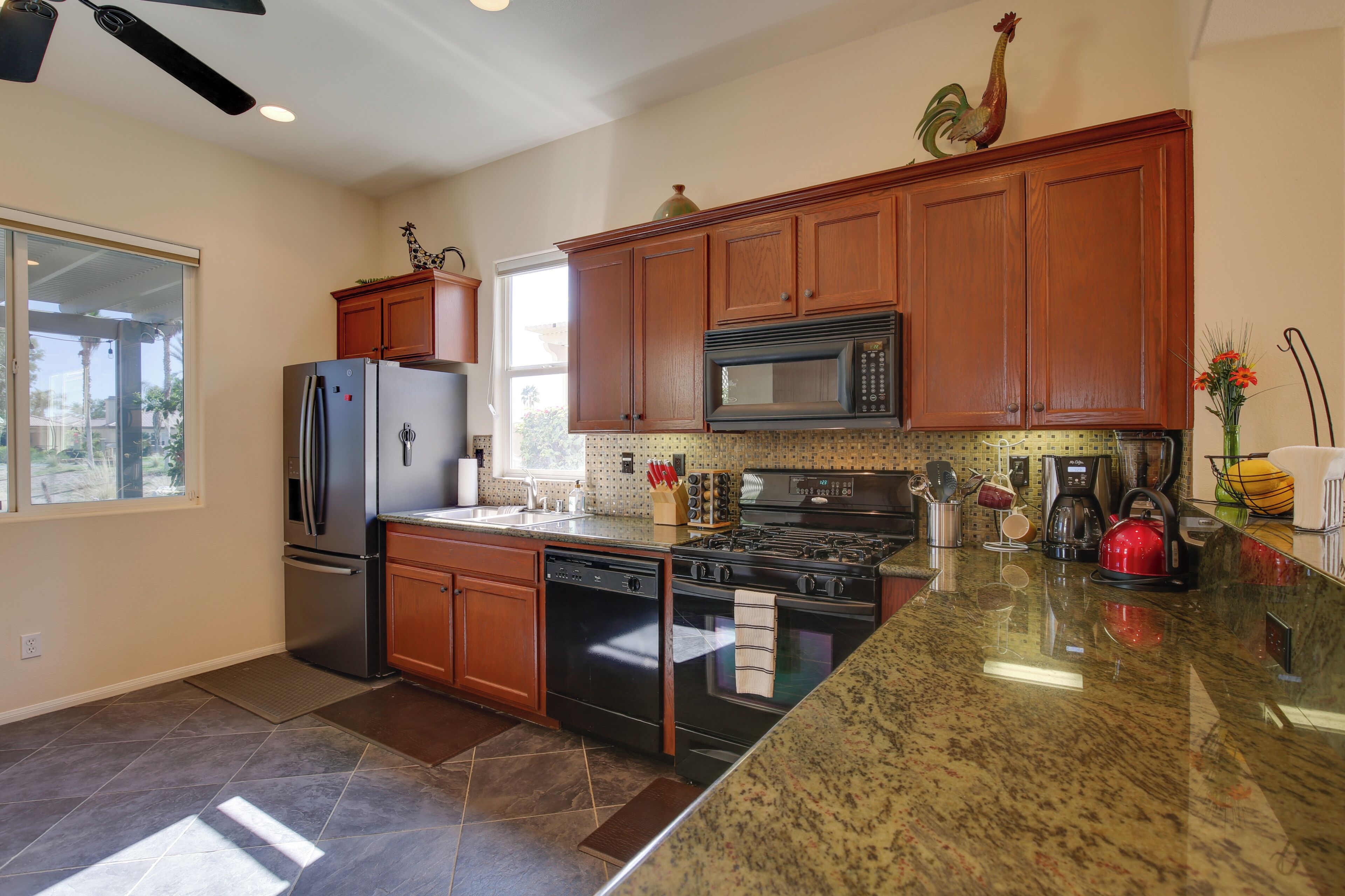 A modern kitchen with wooden cabinets, stainless steel appliances, and a granite countertop.
