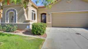 A residential house with a garage, a well-maintained lawn, and a small garden. - 1 Mi to Coachella: Serene Retreat w/ Pool Access (Indio)