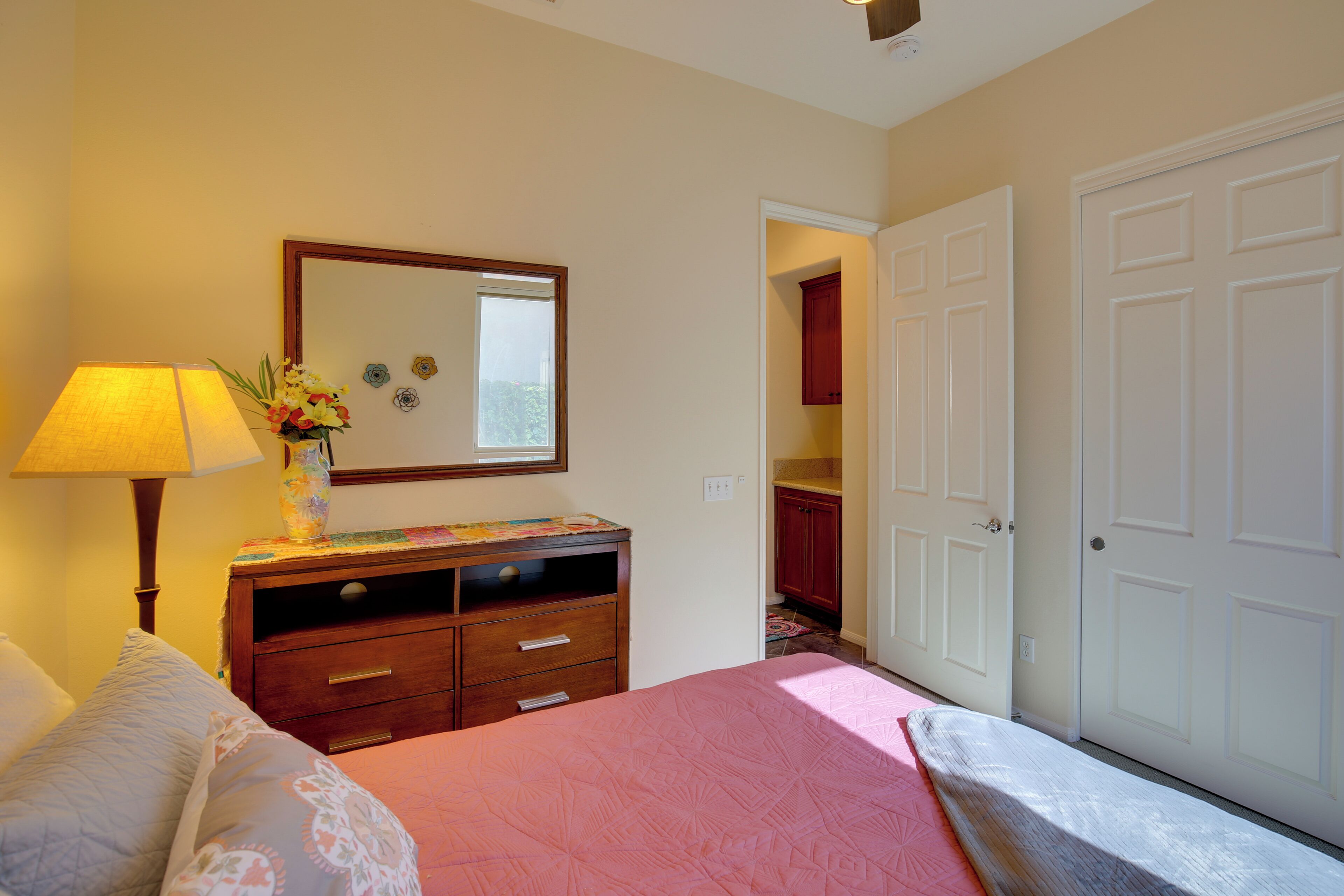 Un dormitorio con cama, cómoda, espejo y puerta que da a un baño.