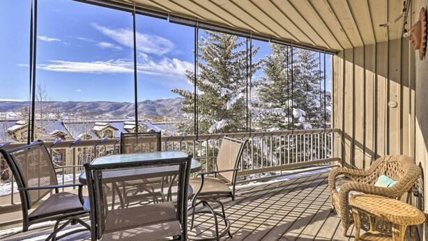 Eine Holzterrasse mit Tisch und Stühlen mit Blick auf eine verschneite Landschaft und Berge.