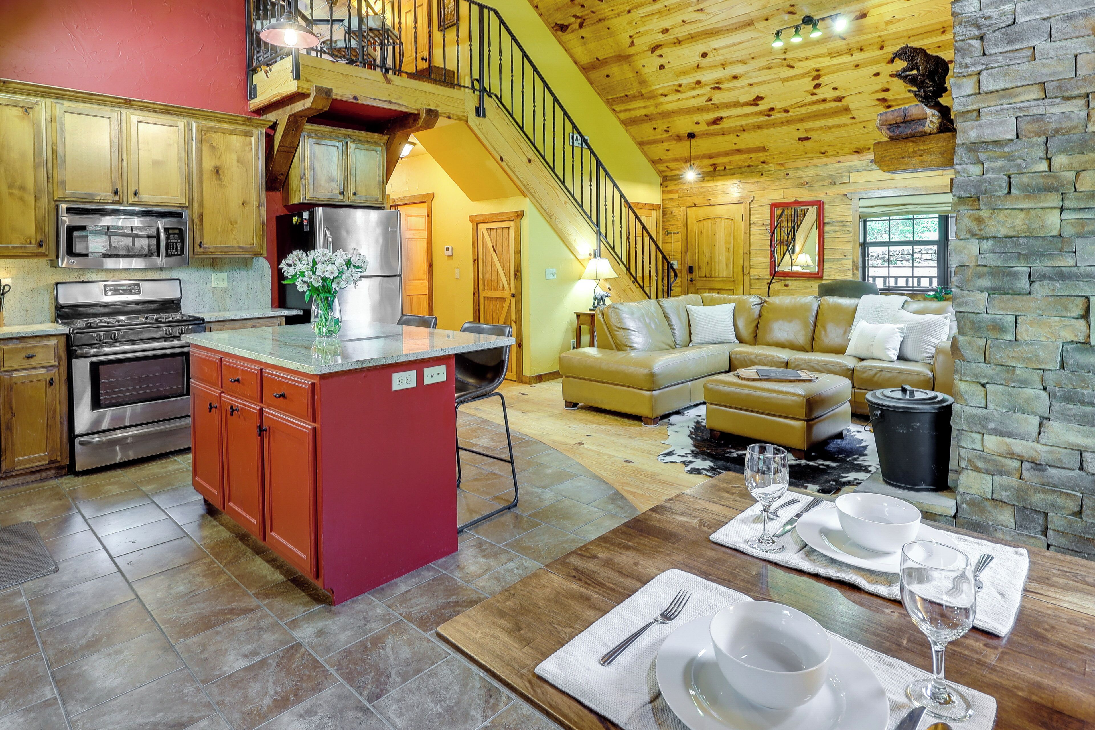 A spacious kitchen with modern appliances, a dining area with a wooden table set for two, and a cozy living room with a sofa and a fireplace.
