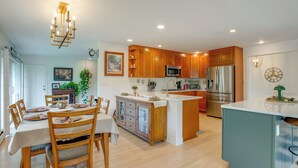 A modern kitchen with wooden cabinets, a central island, and a dining area with a table and chairs.