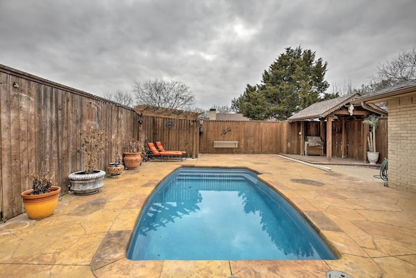 A backyard with a swimming pool, wooden fence, and outdoor seating area.