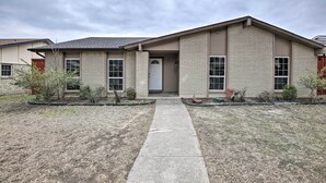 A single-story house with a front entrance, a small porch, and a pathway leading to the door. - Garland Home w/ Private Pool & Yard! (Garland)