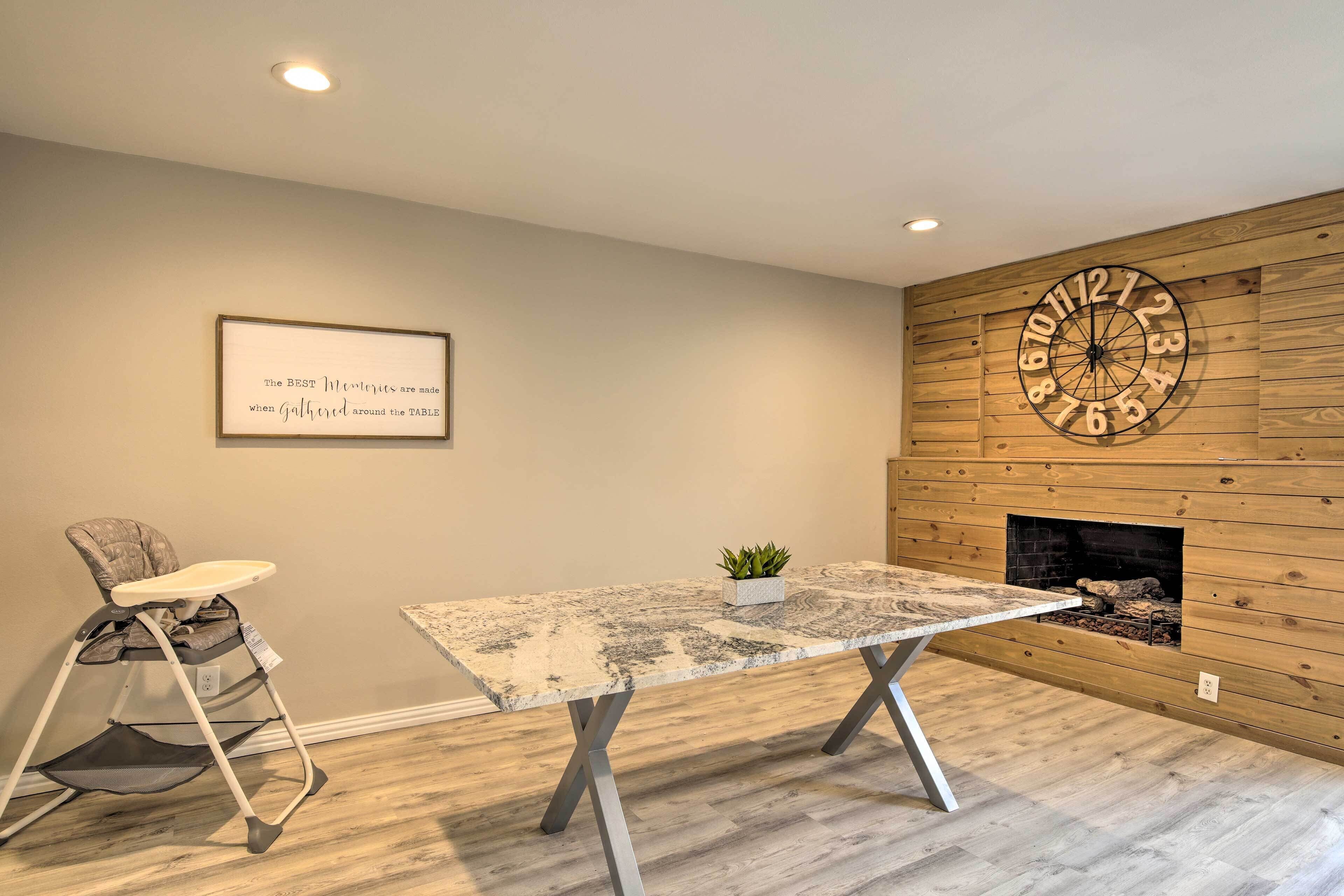 A room with a wooden wall, a clock, a framed quote, a baby stroller, and a fireplace.