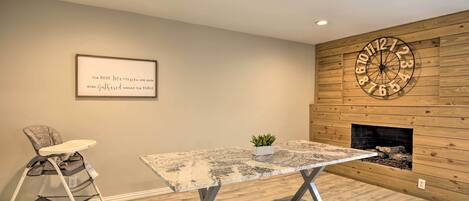A room with a wooden wall, a clock, a framed quote, a baby stroller, and a fireplace.