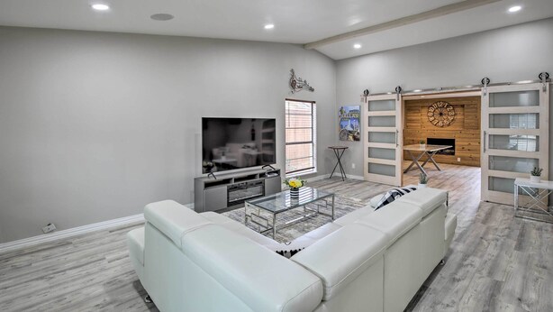 A modern living room with a white sofa, a glass coffee table, a flat-screen TV, and a fireplace. - Garland Home w/ Private Pool & Yard! (Garland)