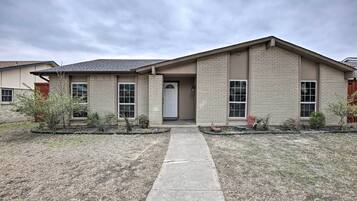 Stylish single-story home with a central entrance and a beautifully manicured lawn.