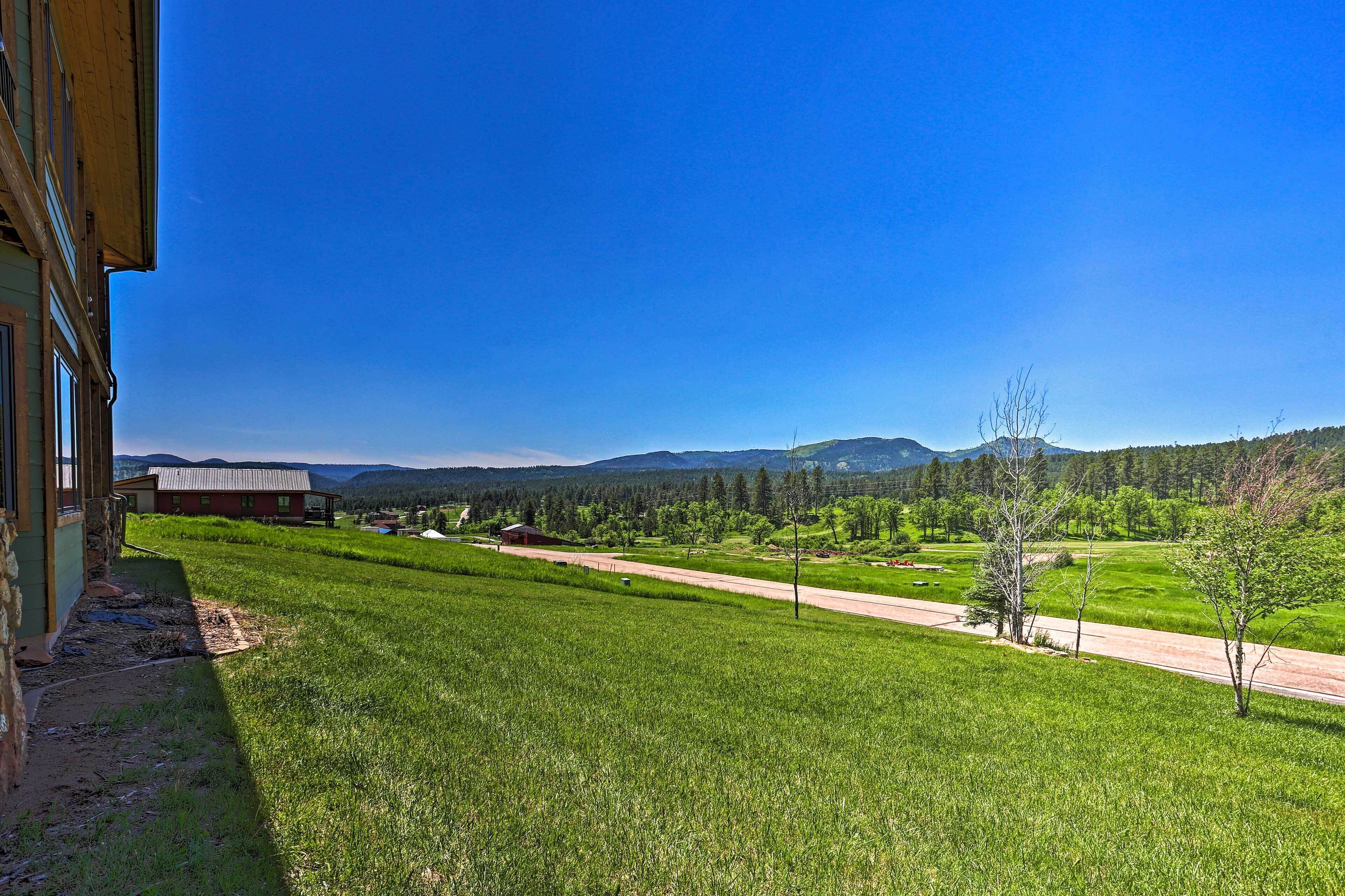 A rural landscape with a road, green fields, and distant mountains.