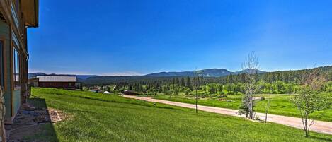 A rural landscape with a road, green fields, and distant mountains.