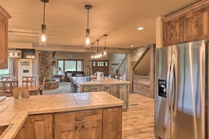 A spacious kitchen with a large island, wooden cabinets, and a stainless steel refrigerator.