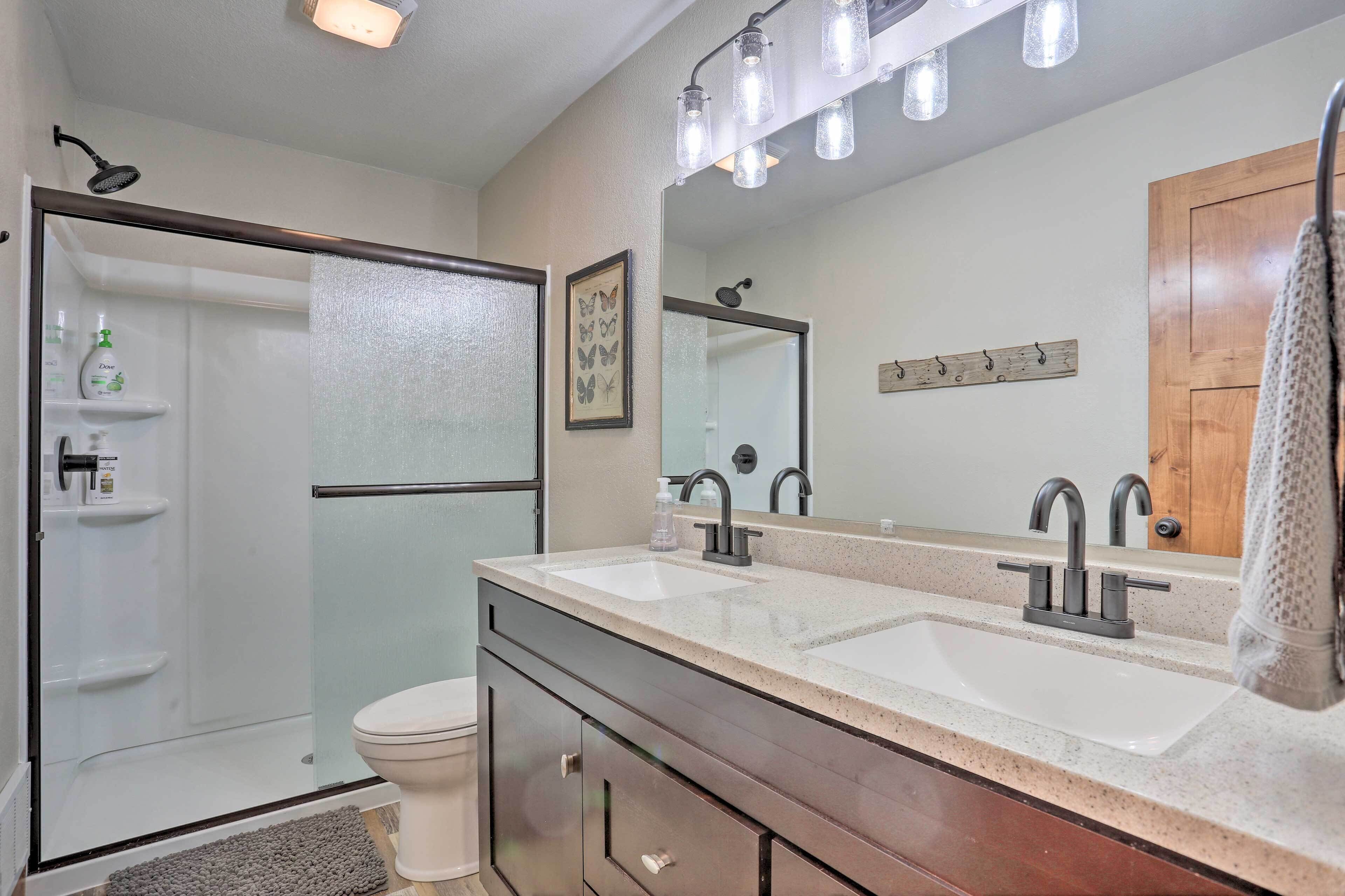 Une salle de bain moderne dotée d’une douche à parois de verre, d’un meuble-lavabo à deux vasques et d’un grand miroir.