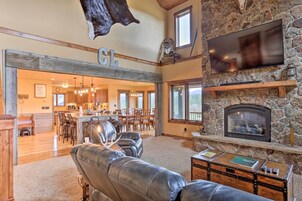 A spacious living area with a stone fireplace, leather sofas, and a dining area with wooden furniture.
