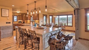 A spacious kitchen with a large island, wooden cabinets, and pendant lighting.