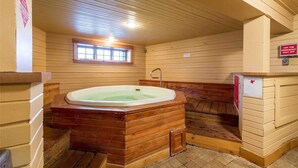 Una cabaña de madera con un jacuzzi, paredes de madera, una ventana y un letrero que indica el apagado de emergencia del jacuzzi.