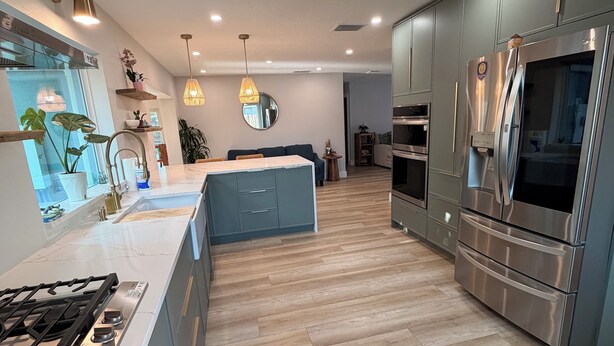 A modern kitchen with a central island, stainless steel appliances, and wooden flooring.