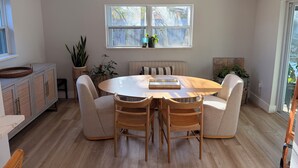 A dining area with a round table, four chairs, a bench, and a cabinet with woven doors.