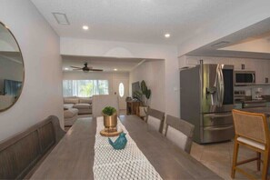 Enjoy dining and socializing in this comfortable space with a central dining table, sofa, and chair.