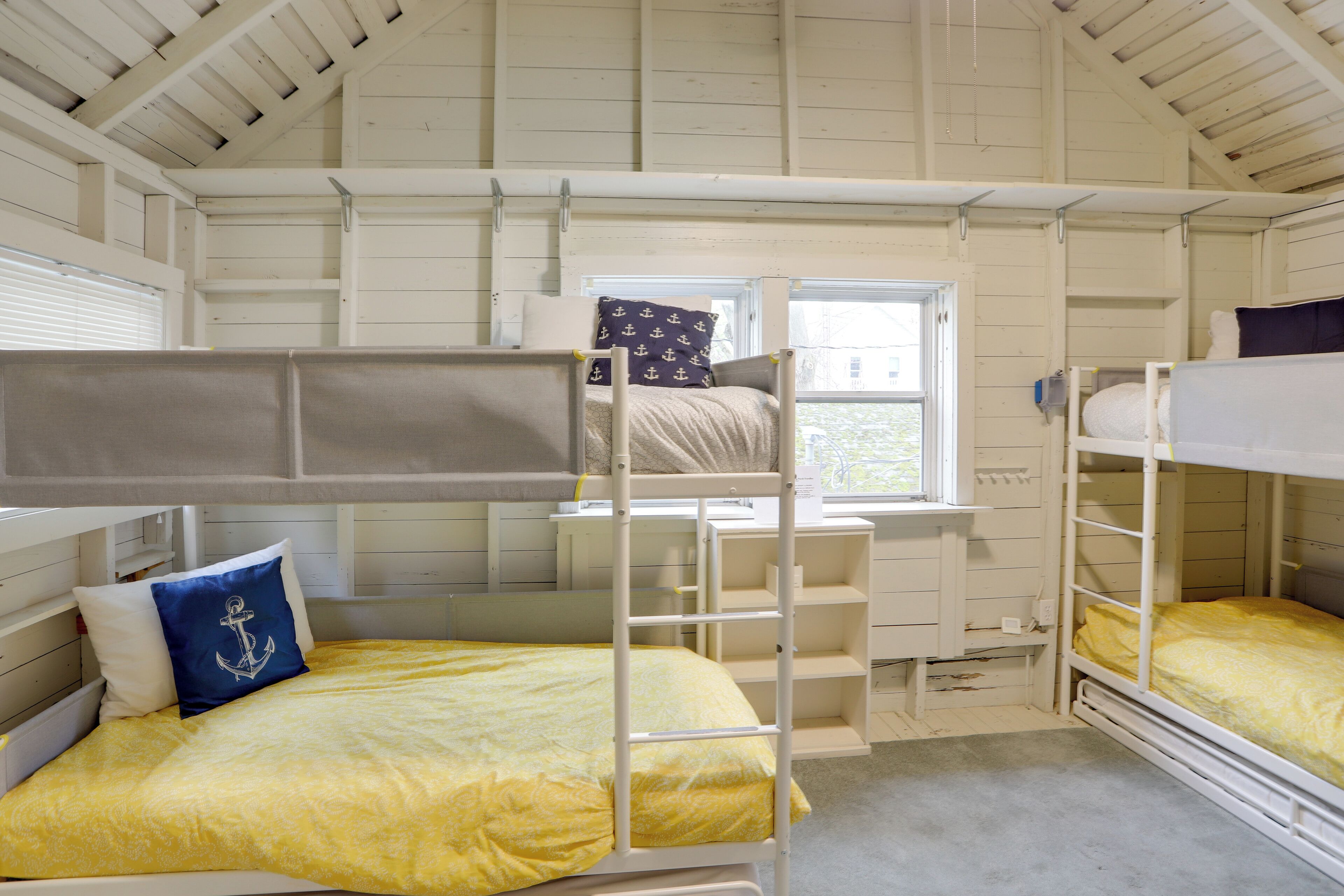 Een slaapkamer met stapelbed, een raam, een bureau en een stoel.