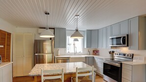 A modern kitchen with a granite countertop, white cabinetry, stainless steel appliances, and a hanging pendant light. - Spacious Lakeside Cottage - 2 Miles to Marblehead! (Marblehead)