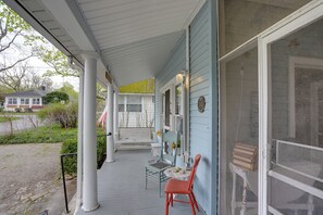 A porch with a white railing, a red chair, and a table with a vase and a book. - Spacious Lakeside Cottage - 2 Miles to Marblehead! (Marblehead)