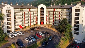 A multi-story hotel with a central courtyard, parking lot, and a view of the surrounding hills. - Gatlinburg Condo w/ Smoky Views: Walk to Town! (Gatlinburg)