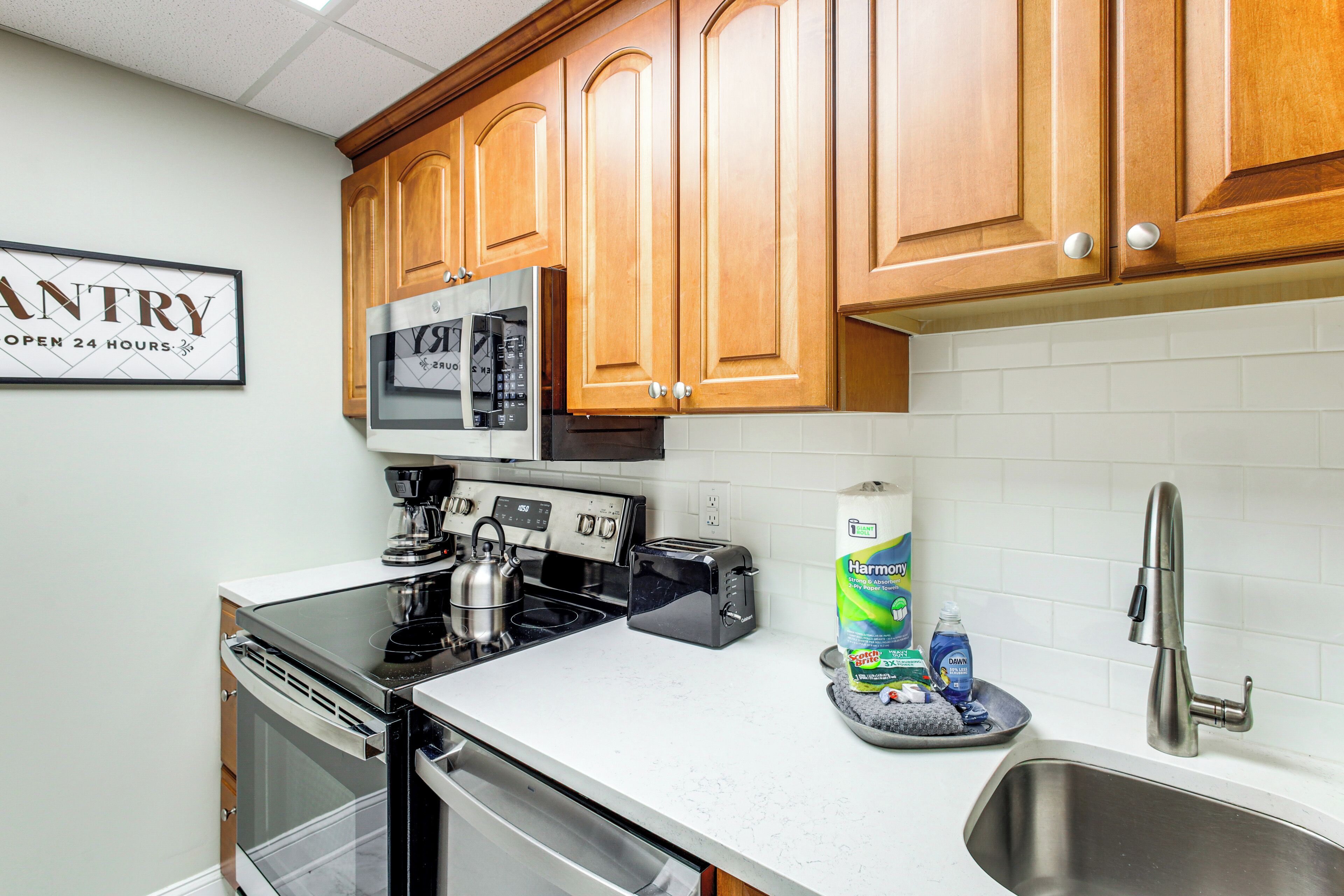 A kitchen with wooden cabinets, a stainless steel sink, a coffee maker, a toaster, and a dish soap dispenser.
